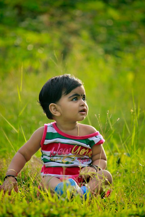 孩子坐在绿草地上的照片