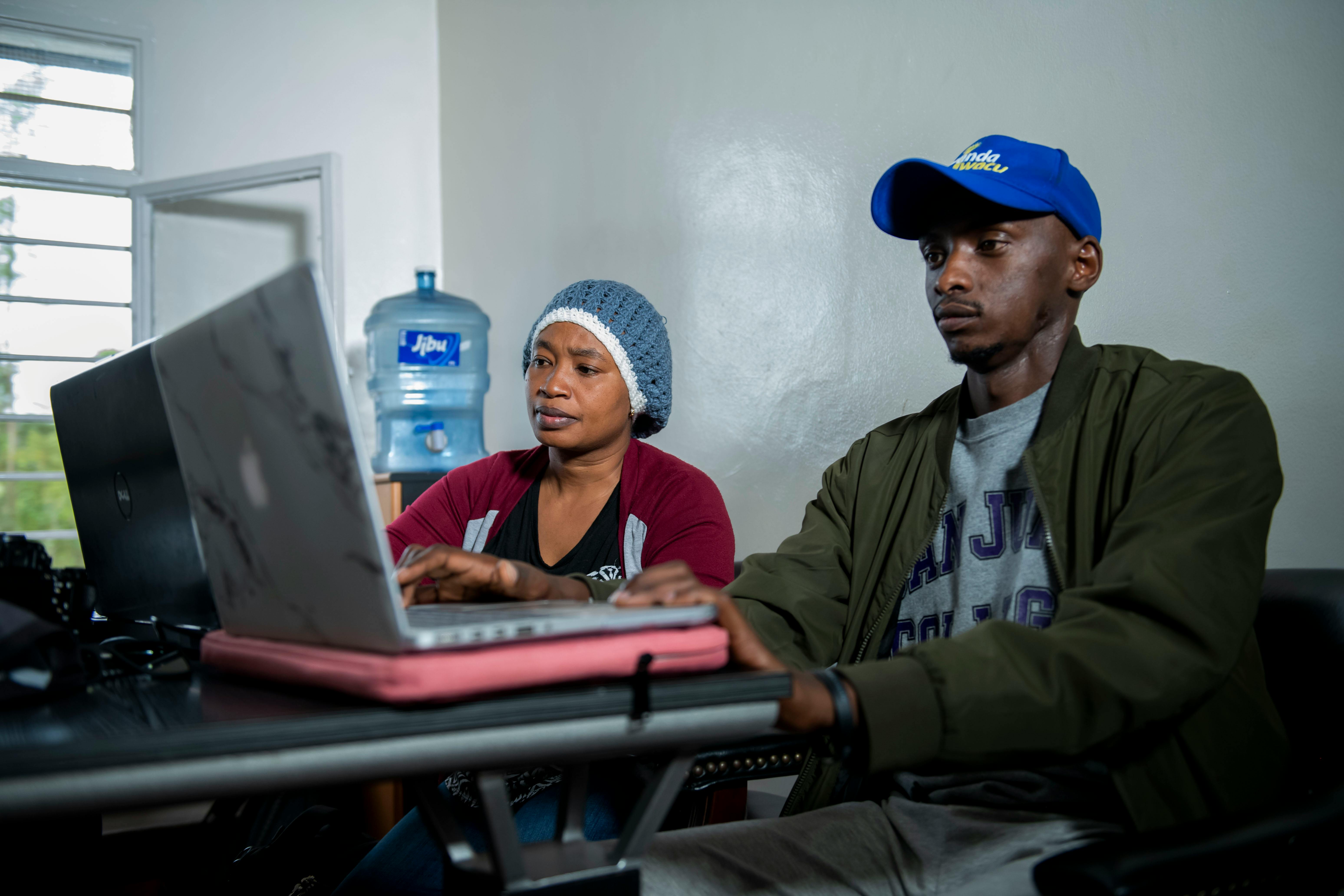 Two adults working collaboratively on laptops at an indoor office desk, emphasizing teamwork.