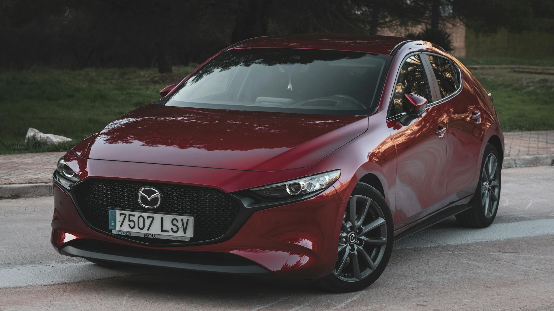 Stylish red Mazda 3 parked outdoors, showcasing a sleek, modern design.