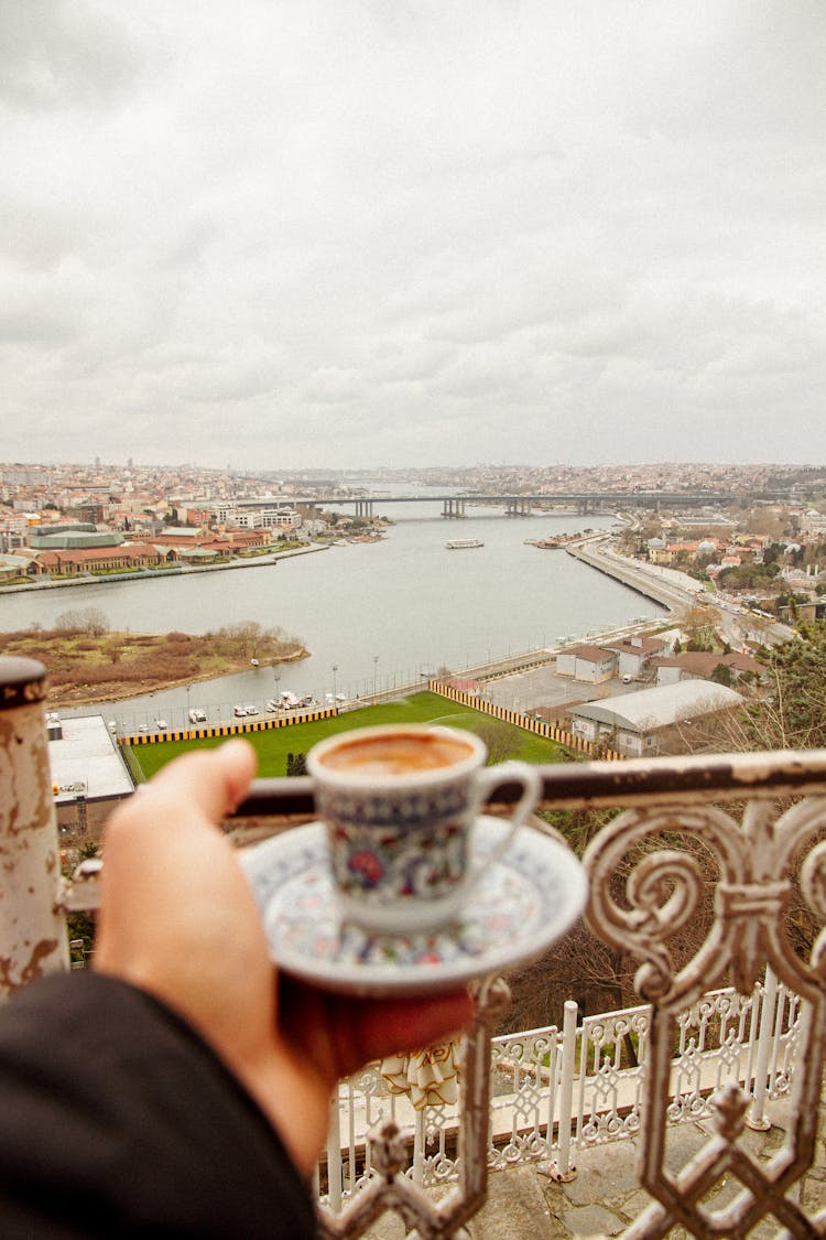 Man Holding A Cup Of Espresso On A Balcony With The View Of Istanbul From The Pierre Loti Hill