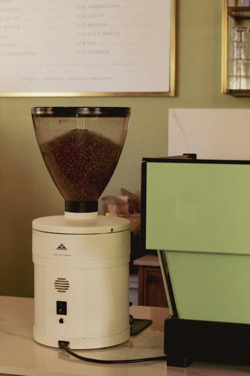 A Large Coffee Grinder next to a Coffee Machine in a Cafe 