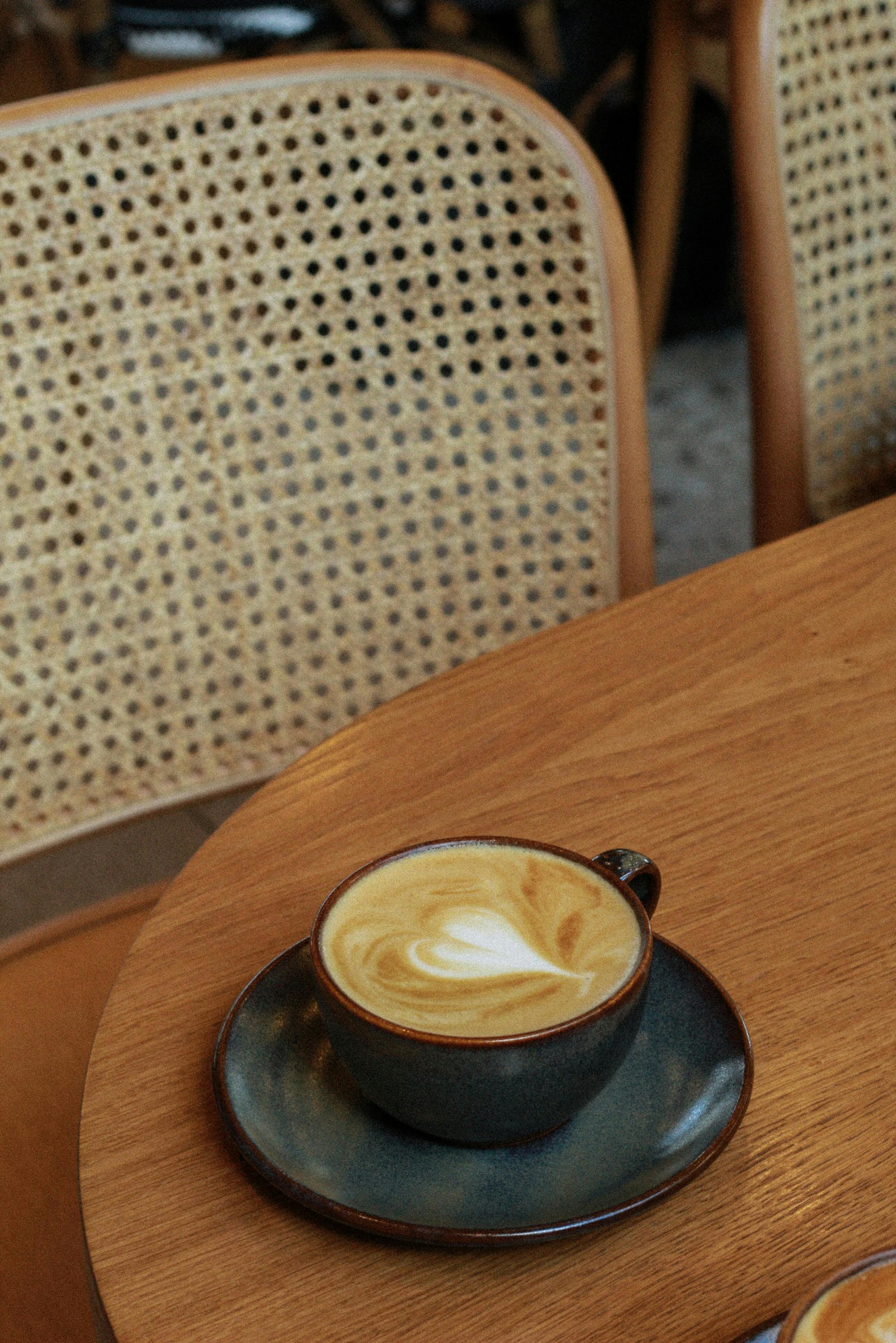 A cozy café scene featuring a latte with heart-shaped foam on a wooden table.