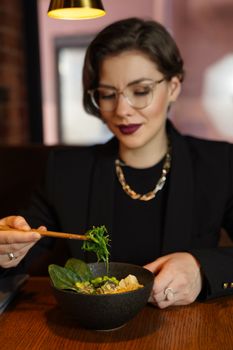 A woman enjoying a healthy meal with fresh greens at a restaurant.