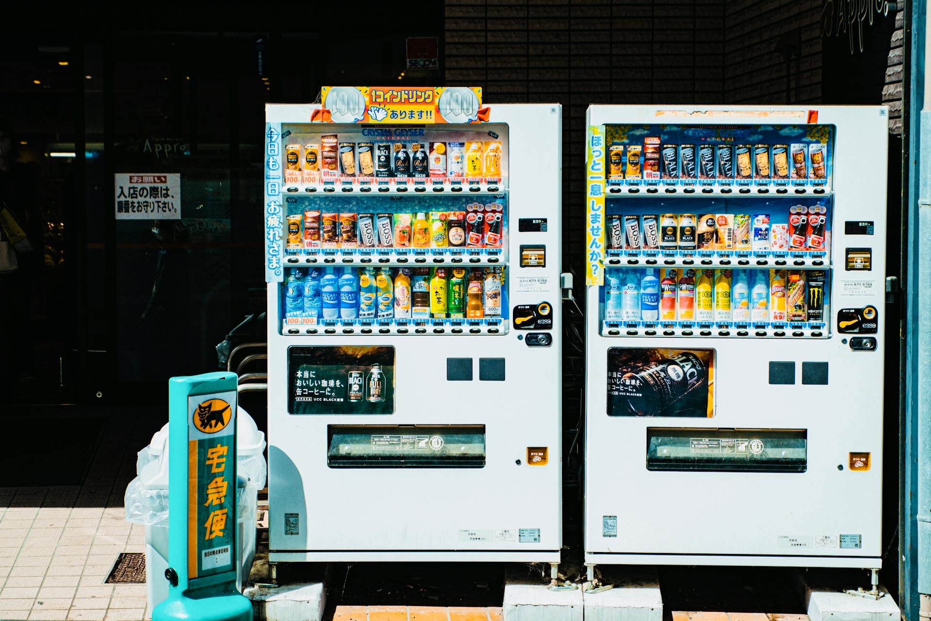 Colorful array of beverages in Japanese vending machines on a sunny city street.