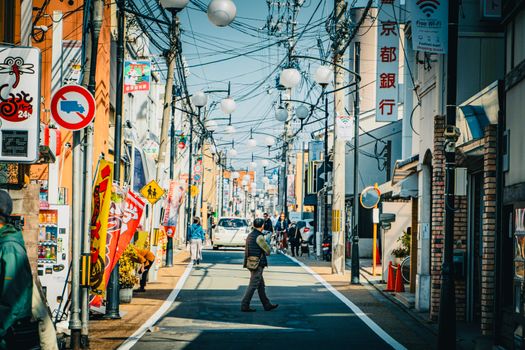 Colorful urban street in Kyoto with pedestrians and traditional signs.