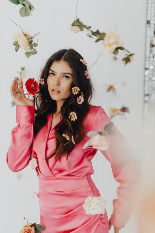 Free Beautiful woman in a pink dress with flowers in studio setting. Soft and elegant style. Stock Photo