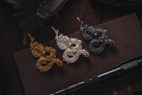 Free Stylish dragon pendants in gold, silver, and bronze arranged artistically on a desk. Stock Photo