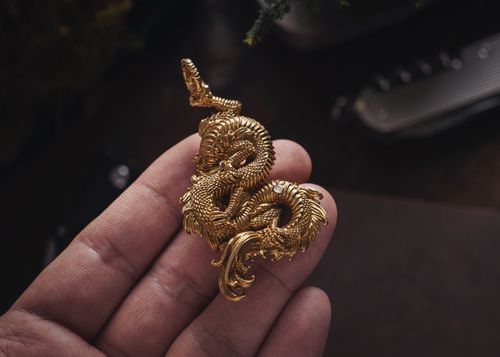 Free Close-up of a handmade golden dragon pendant being held in a human hand. Stock Photo
