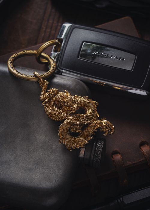 Free Close-up of a detailed dragon pendant keychain placed with luxury car keys on a leather surface. Stock Photo
