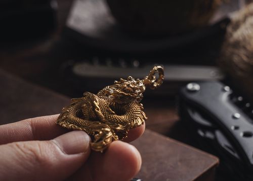 Free Close-up of a golden dragon pendant being held, showcasing its detailed craftsmanship. Stock Photo