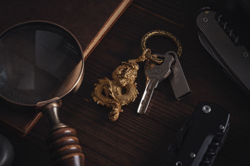 Free Intricately designed golden dragon keychain with keys, magnifying glass, and metal tools. Stock Photo
