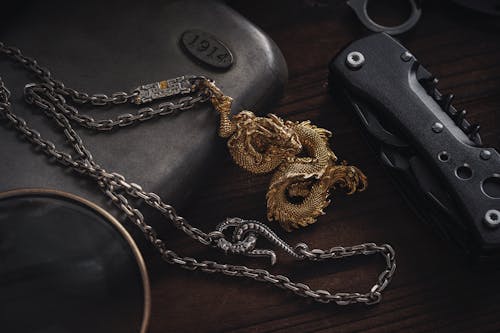 Close-up of a Dragon Pendant Lying next to a Multi Tool on a Desk 