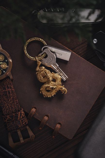 Artistic shot of a golden dragon keychain atop a vintage leather notebook.