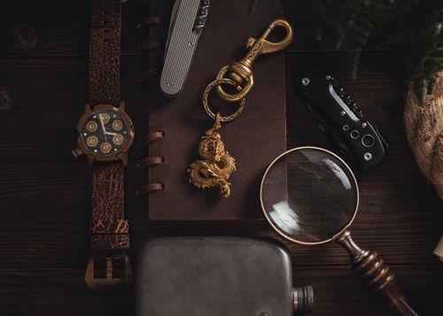 Free Close-up of a stylish desk setup featuring a dragon pendant, magnifying glass, and various accessories. Stock Photo