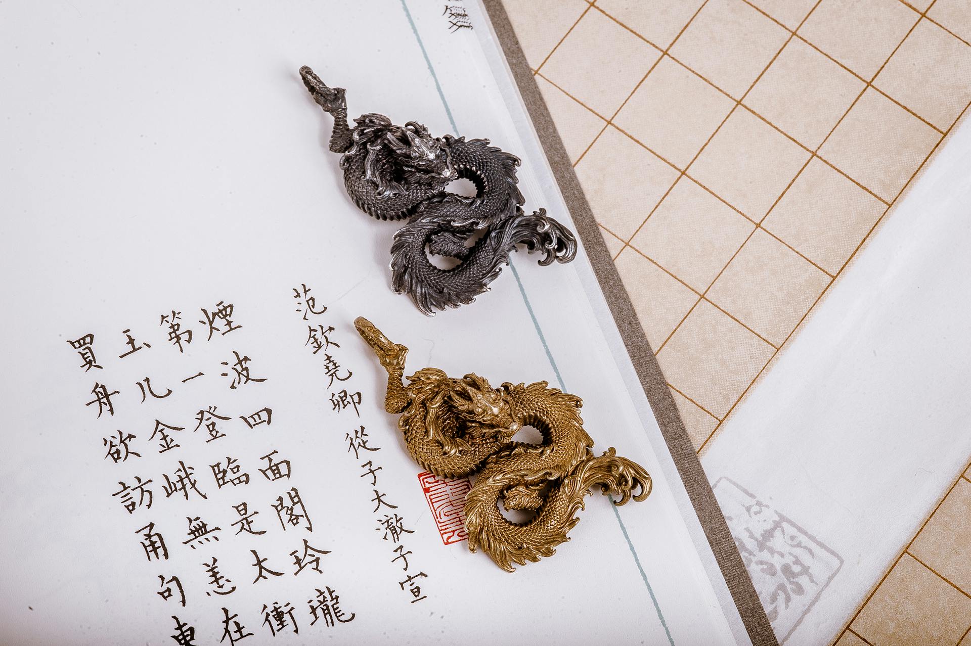 A Silver and Golden Dragon Pendants Lying in a Page with Chinese Symbols