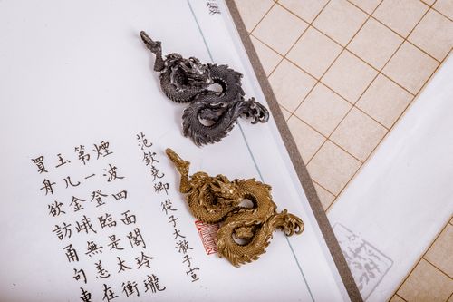 Free Golden and silver dragon pendants showcased on traditional Chinese calligraphy paper. Stock Photo