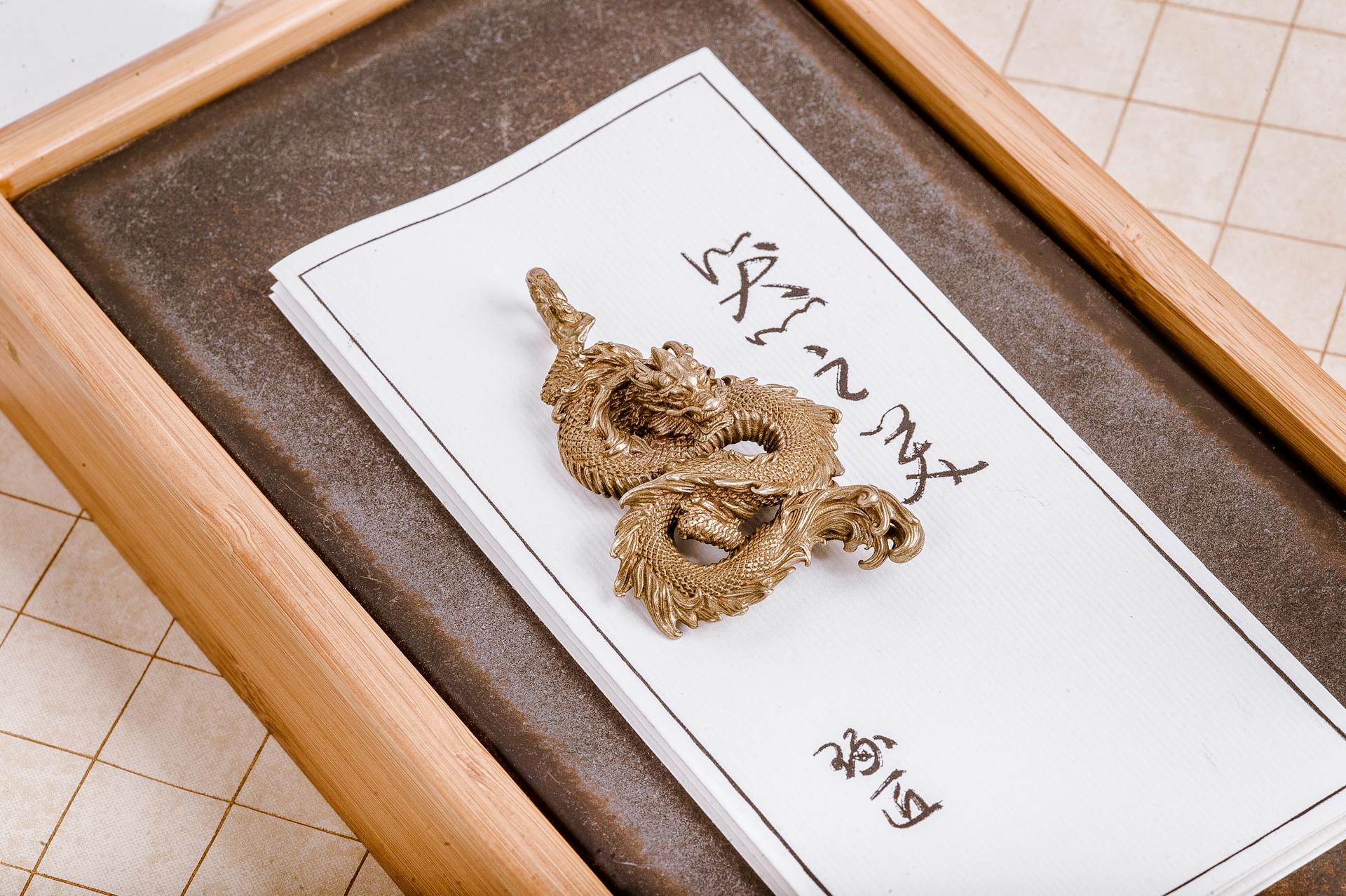 Close-up of a Golden Dragon Pendant Lying on a Board with Chinese Symbols