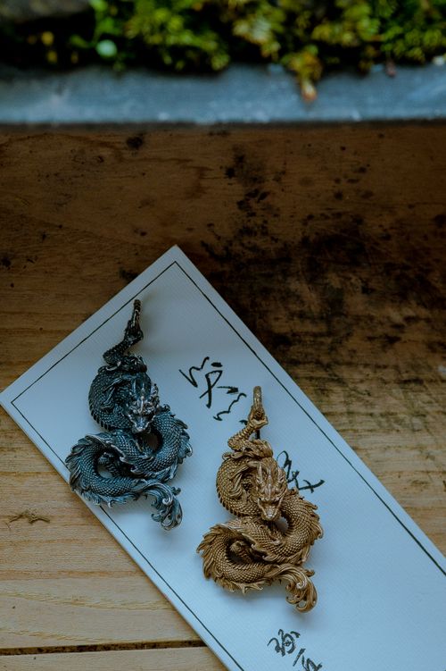 Free Intricately crafted golden and silver dragon pendants resting on wood, exuding elegance. Stock Photo