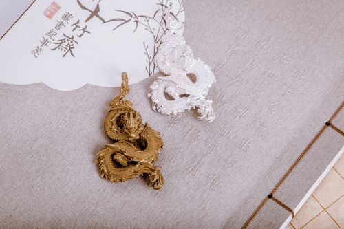 Free Golden and silver dragon pendants on decorative paper with Asian calligraphy. Stock Photo