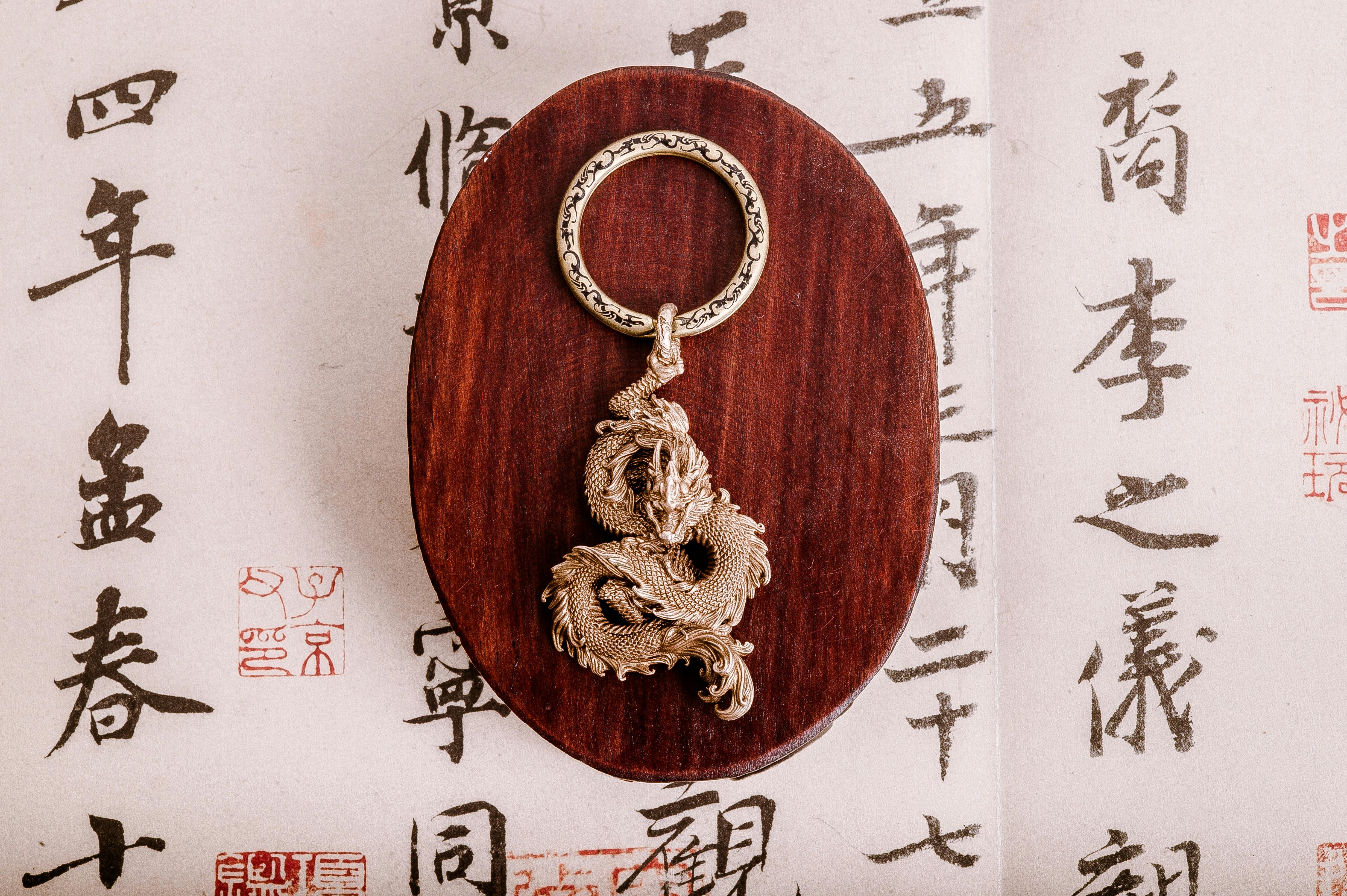 Dragon Keychain Displayed on Wooden Board · Free Stock Photo