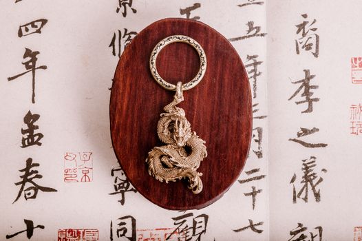 Elegant dragon keychain displayed on a wooden board with intricate background patterns, perfect for decor.