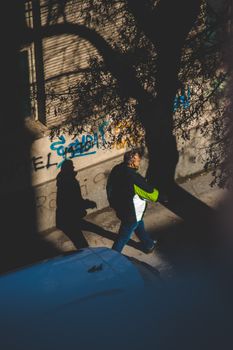 Overhead view of a man walking on a shadowy street in Niš, Serbia.