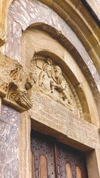 Detailed stone carving of figures above an ancient wooden doorway.