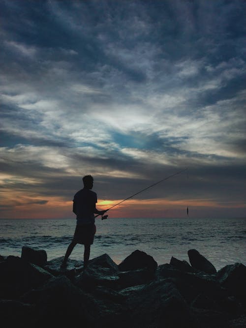 Man with Fishing Rod by Sea at Dawn