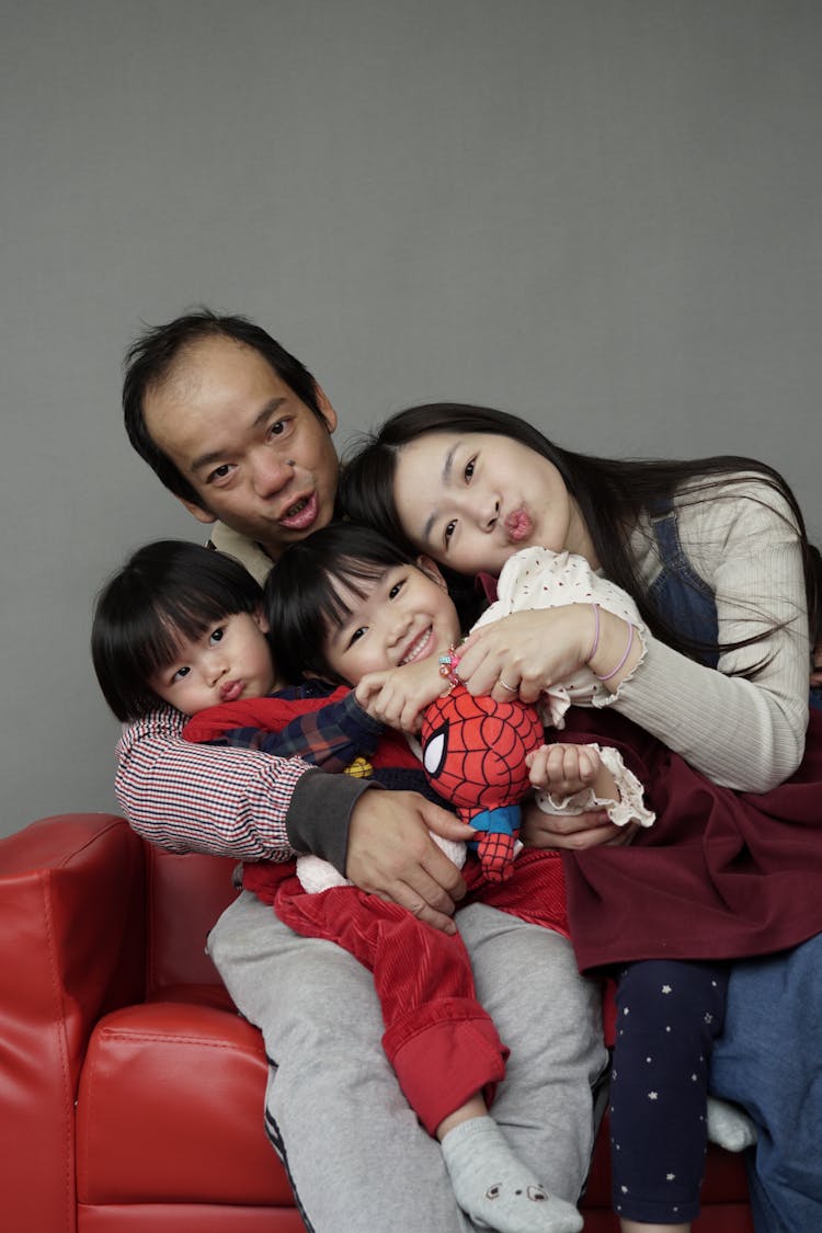 Happy Family With Children Posing On Chair In Studio