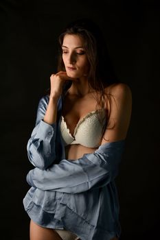 A woman in fashionable attire posing in a studio setting with soft lighting.