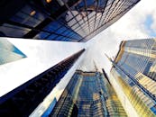 在现代城市景观中，采用低角度动态拍摄高耸的摩天大楼及其反光玻璃立面