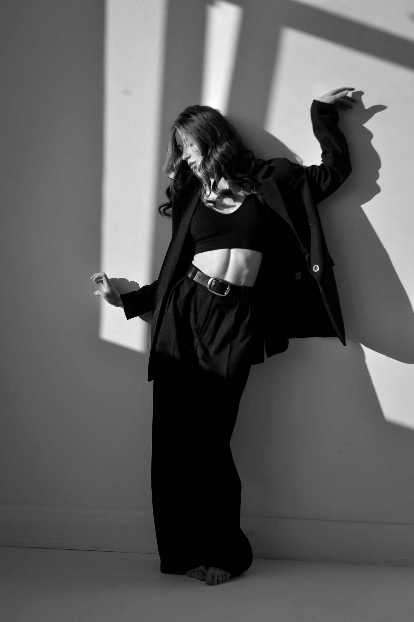 A model posing for a black and white portrait in tailored trousers