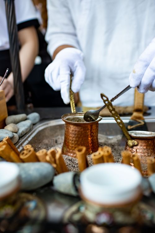Free Close-up of a barista brewing coffee in a copper pot using white gloves. Stock Photo