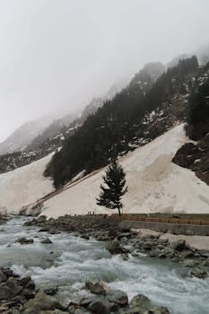 Breathtaking view of snow-covered mountains and flowing river in winter's embrace, captured in high clarity.