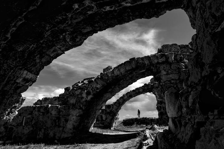 Silhouette Of Man Standing On Rock Near Stone Cave