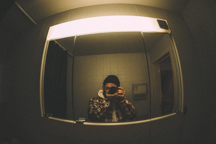 A Man Taking A Photo In A Bathroom Mirror