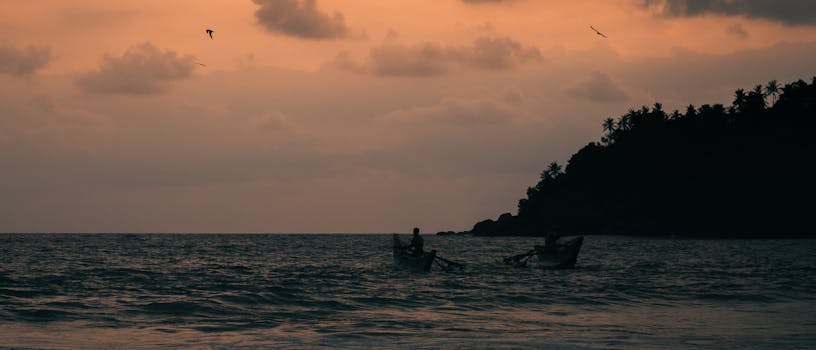 Two fishermen casting nets at sunset in Mirissa, Sri Lanka. A tranquil coastal scene.