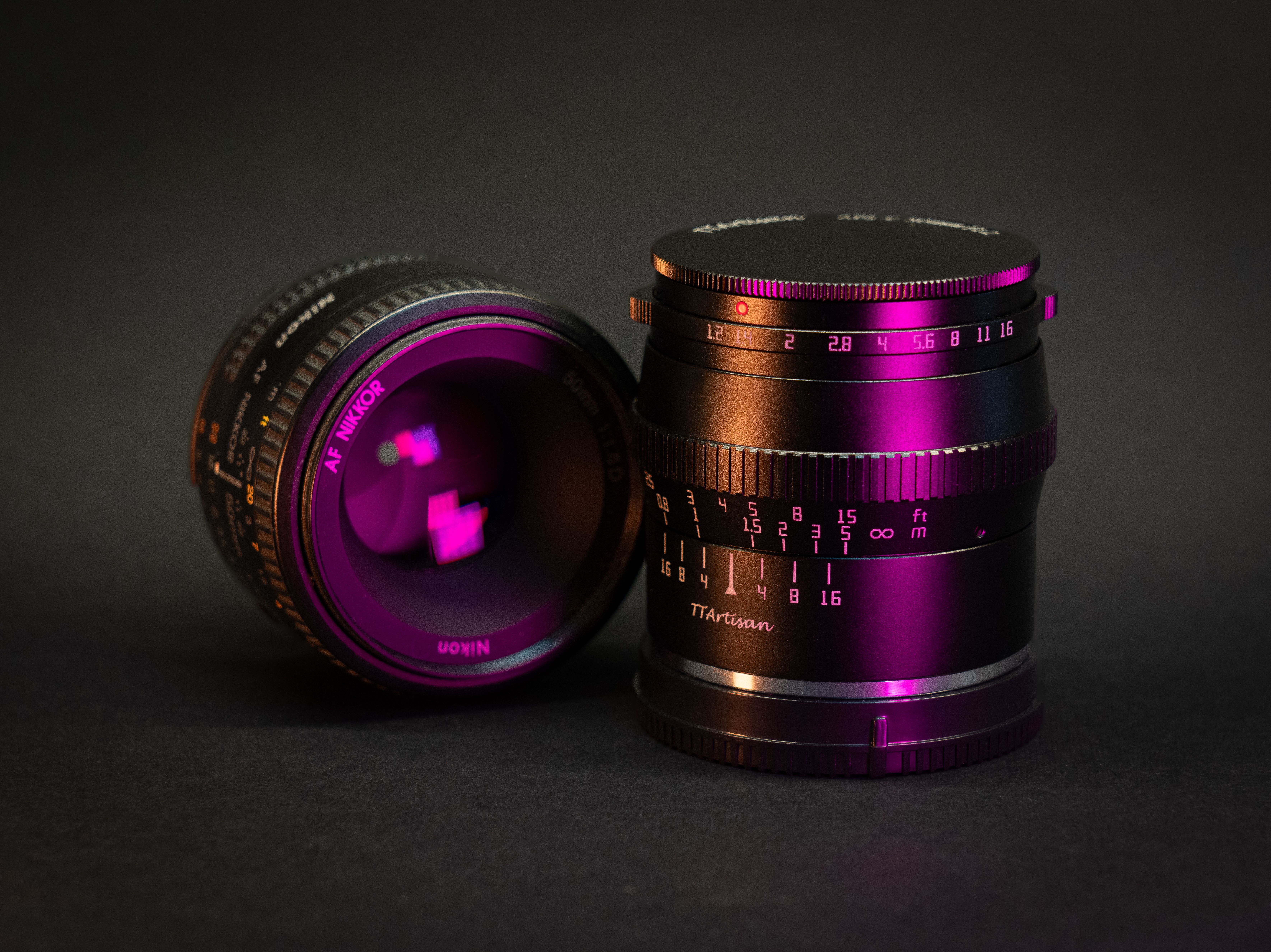 Detailed close-up shot of Nikon and TTArtisan camera lenses with vibrant lighting on a dark background.