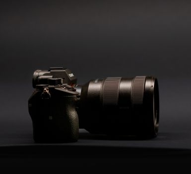 Side view of a DSLR camera with a zoom lens against a dark background, highlighting technology.