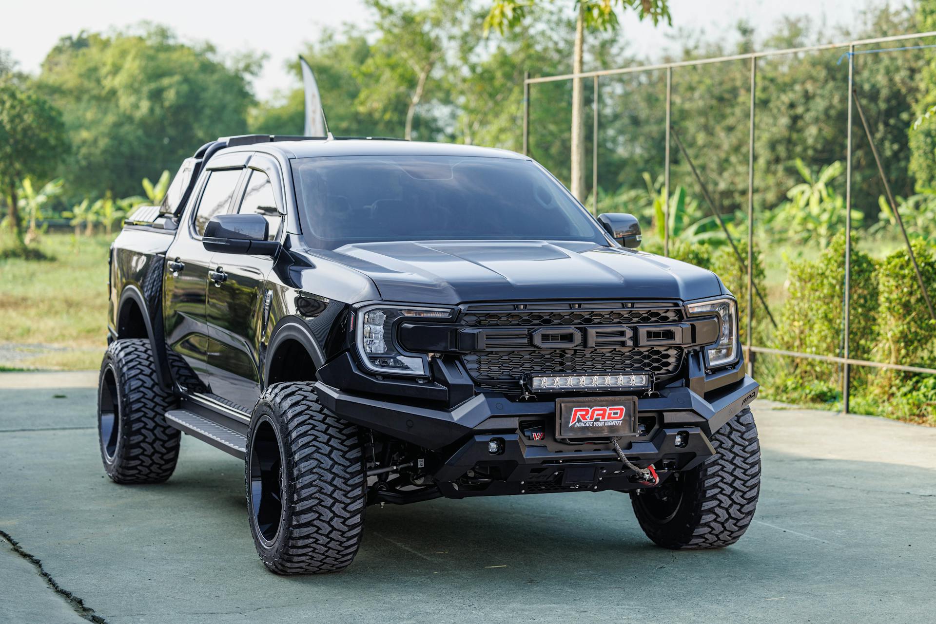 A robust black pickup truck with large tires and unique design parked outdoors on a clear day.