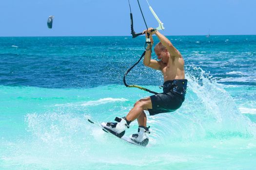 Man enjoying an exhilarating kiteboarding experience in the vibrant turquoise ocean on a sunny day.