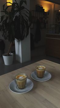 Warm cafe interior featuring two lattes on a wooden table, creating a relaxing atmosphere.