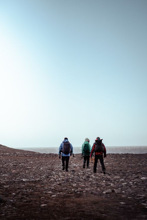 Free Three adventurers hiking on a rocky coastline, showcasing outdoor exploration and travel. Stock Photo