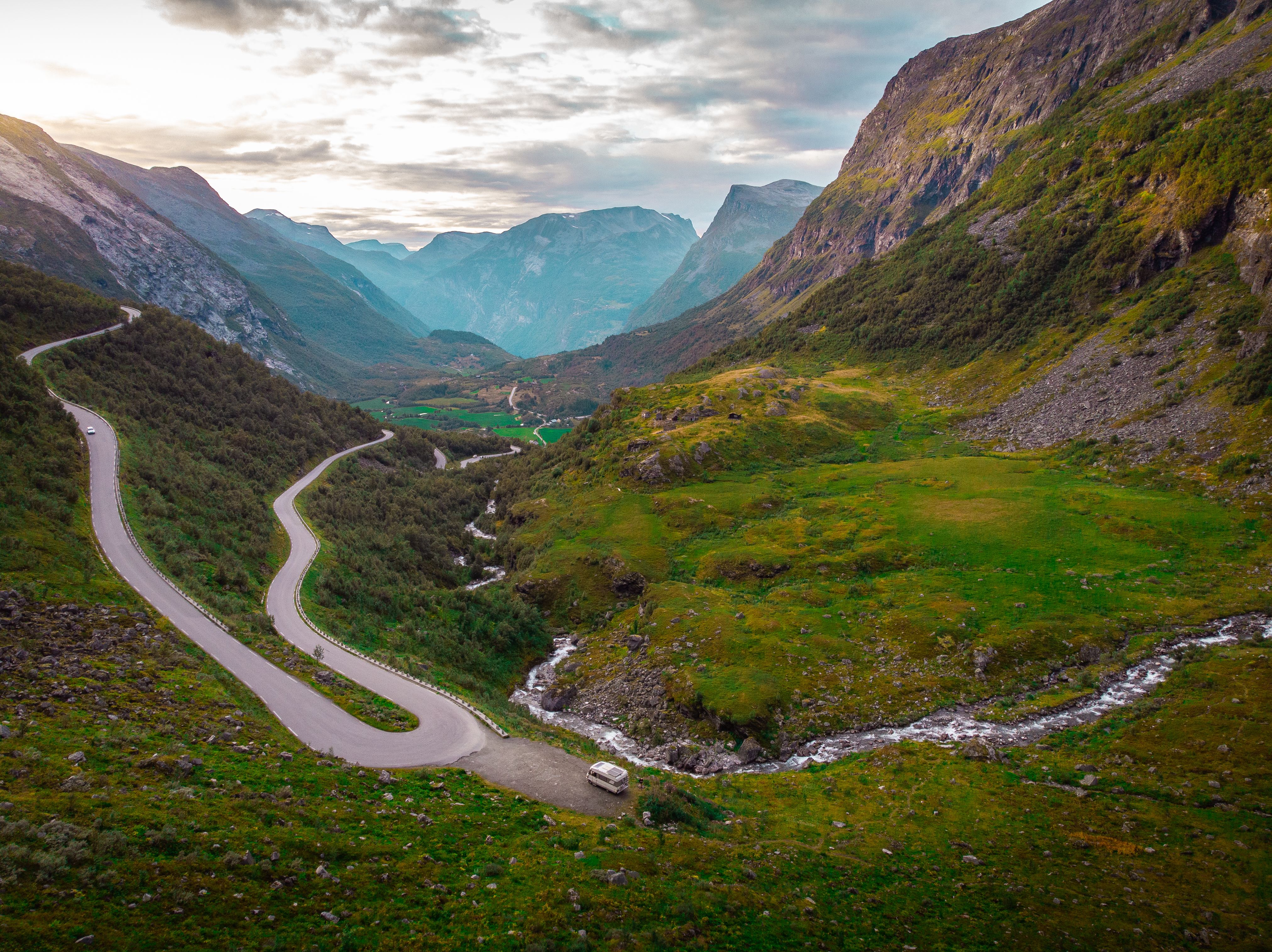 A winding road through lush mountains in Djupevatn, Norway, captured in vibrant detail.