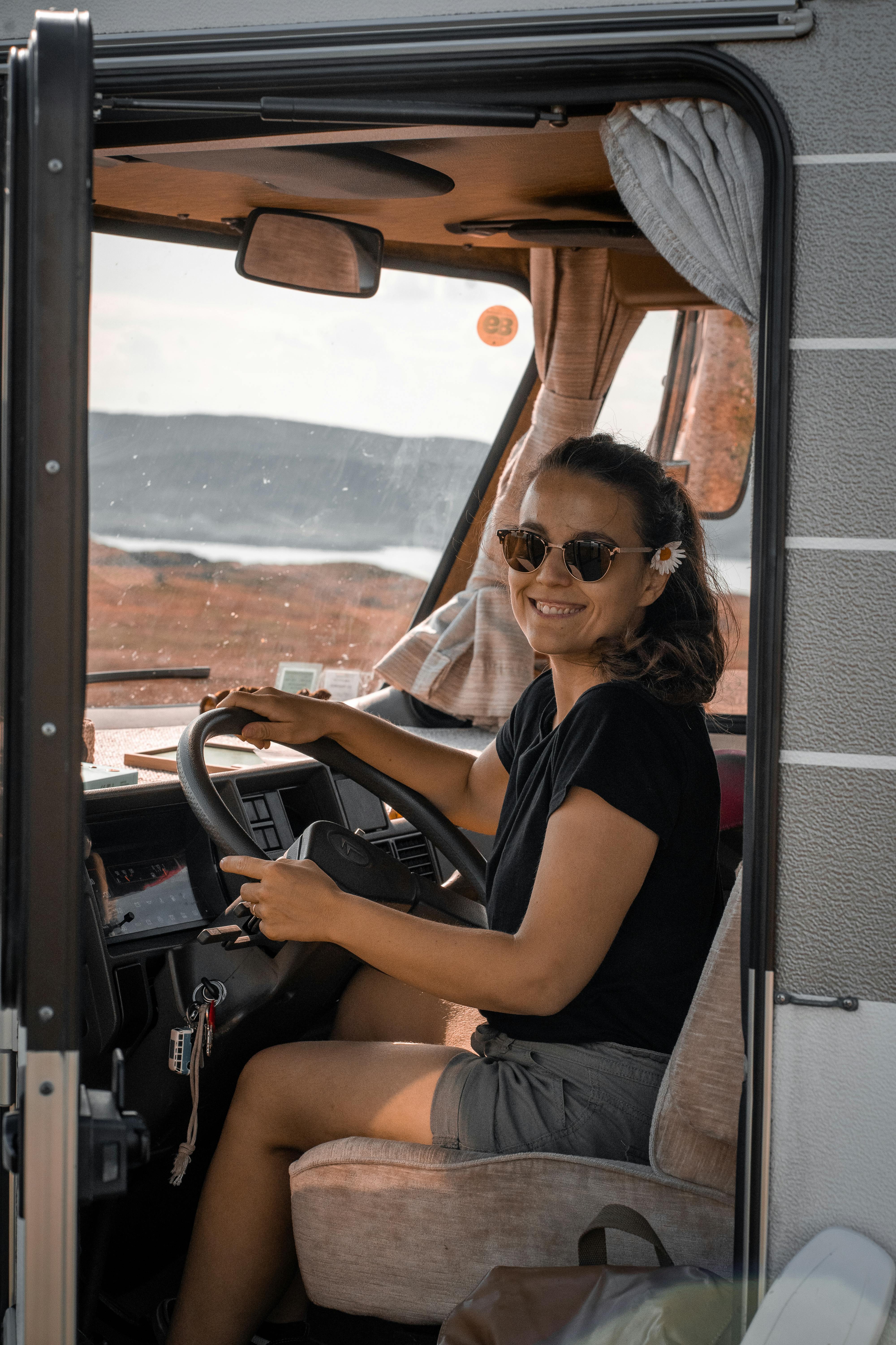 Young woman driving a camper van in scenic Norway landscape. Adventure and travel in style.