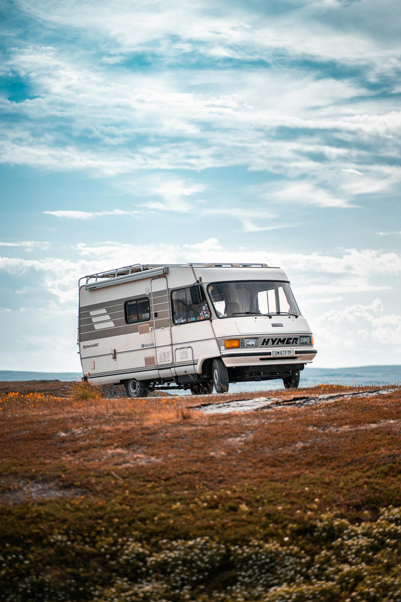 Bobil parkert i åpent landskap ved Vardø – klar blå himmel.