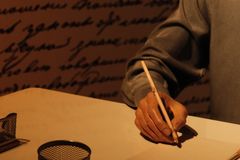 Close-up of hand writing at a desk with vintage decor and warm lighting.