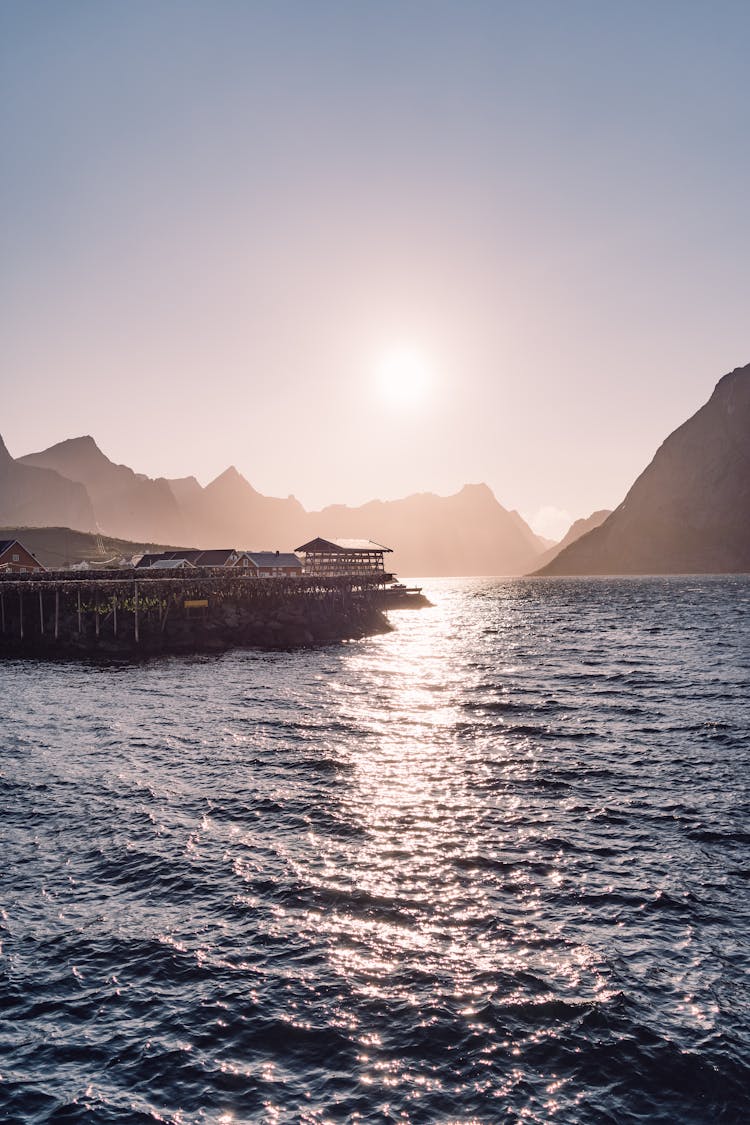 View Of Buildings On The Shore And Silhouetted Hills Of Lofoten Islands, Norway 