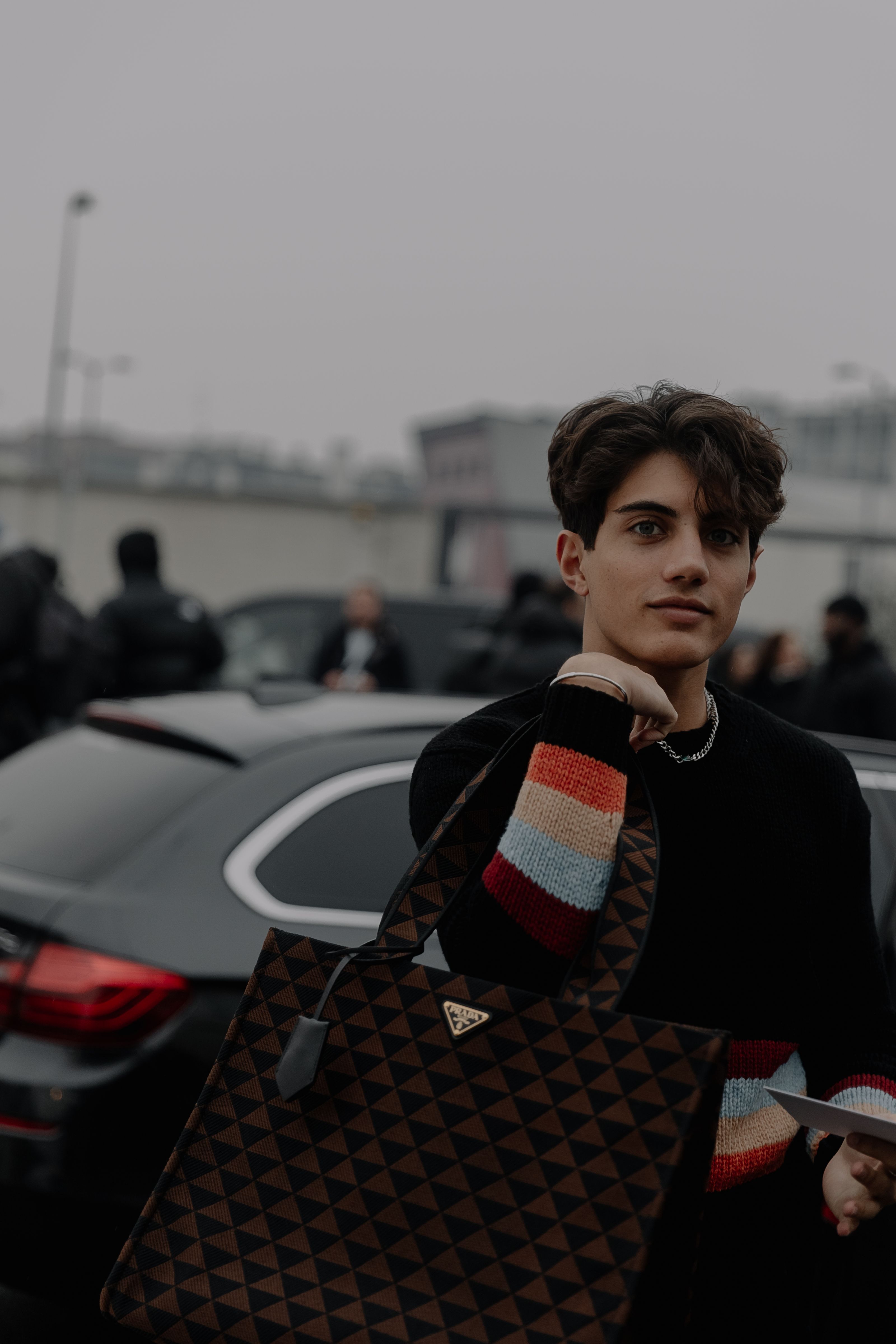 Adulto estiloso posando com bolsa de designer na rua de Milão, demonstrando vibrações de moda urbana.