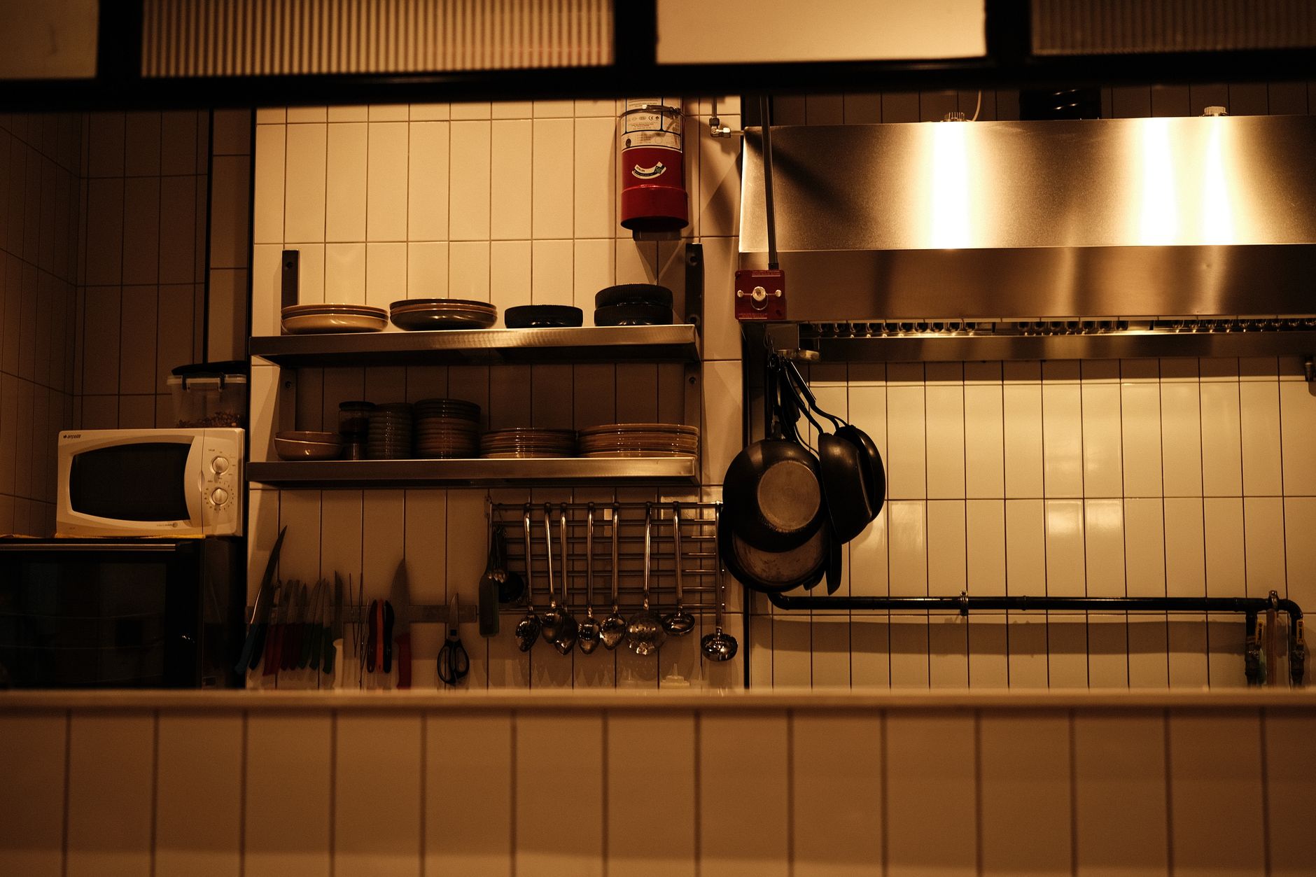 A well-organized restaurant kitchen with utensils, pans, and a microwave oven.